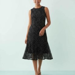 robes à pois noirs et blancs bretelles longue fines portee par une femme avec col rond et coupe midi evasee
