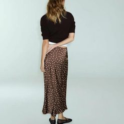 jupes à pois cordon serrage satin midi imprimé 1 jupe midi satinée marron à pois blancs portée par une femme jeune et élégante