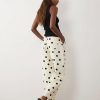 jeans à pois crème bouffant design pantalon coupe large porté par une femme vue de profil avec un débardeur noir
