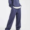 joggings à pois bleu ample pantalon de jogging porté par une femme avec un sweat à capuche assorti et des baskets sur fond bleu