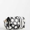 sacs à main à pois réglable bandoulière mini monochrome en cuir noir et blanc porté par une femme en blazer noir élégante