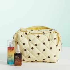 trousses à pois volantés bords de toilette vanille française matelassée jaune avec motifs à pois marrons et fermeture éclair posée à côté de flacons de soins cosmetiques