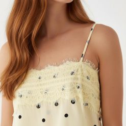 nuisettes à pois longue dentelle robe fines bretelles avec bordures imprimé jaune pastel portée par un mannequin sur fond bleu