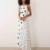 robes asymétriques à pois noirs nageur ourlet dos longue variés blanche sans manches portée par un mannequin sur fond neutre