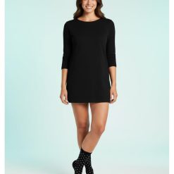 chaussettes à pois pailletés fantaisie chic femme noir portées par une femme en robe noire sur fond bleu clair