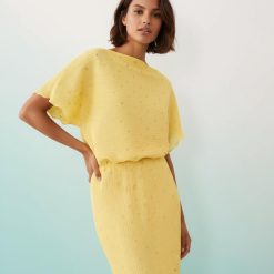 robes à pois jaune longue plissée épaules dénudées motif métallisé fluide ajustée à la taille portée par un mannequin