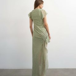 robes mousseline à pois verts longue asymétrique smocké détail ourlet vue de dos portée par un mannequin avec des volants sur le côté et des manches courtes
