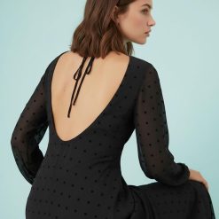 robes à pois années 50 noir floqués en mousseline longue manches ange portée par une femme avec des talons noirs