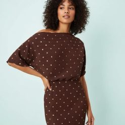robes à pois jaune longue plissée épaules dénudées métallisé marron portée par un mannequin sur fond bleu clair