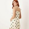 robes à pois jaune courte denim noué aux épaules couleur crème avec des pois noirs portée par une femme rousse vue de dos