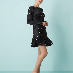 robes évasées à pois et manches courte en satin noire a volant portee par une femme sur fond bleu