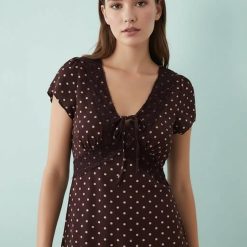 robes bustier à pois bordeaux dentelle détail nouée devant mi-longue portée par un mannequin avec manches courtes et décolleté v sur fond bleu