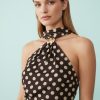 robes asymétriques à pois en tulle courte dos nu motif marron élégante femme noire posant devant un fond bleu clair avec coiffure afro naturelle sophistiquée