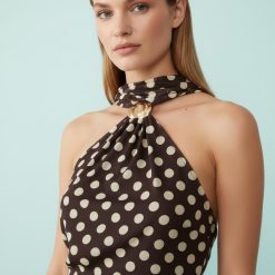 robes asymétriques à pois en tulle courte dos nu motif marron élégante femme noire posant devant un fond bleu clair avec coiffure afro naturelle sophistiquée