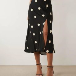 robes évasées à pois manches col bénitier oversize fendue noirs portée par une femme avec des sandales à talons noirs