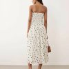 robes évasées à pois fronces bandeau mi longue crème imprimé portee par un mannequin sur un fond bleu pastel