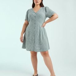 robes évasées à pois couronne de lauriers courte boutonnée patineuse femme portant une robe verte à motifs floraux blancs sur fond bleu clair