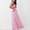 robes mousseline à pois rose vale volantées épaules longue avec découpe à la taille et dos nu portée par un mannequin avec des talons noirs