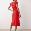 robes longues à pois rouge fluide col v avec mancherons vue de dos portée par un mannequin avec des sandales beige et une pochette