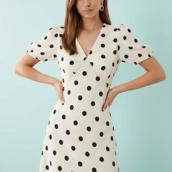 robes longues marron à pois v col gris mouton portée par une femme aux cheveux bruns sur fond bleu clair