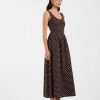 robes longues marron et blanc à pois design sans manches décolleté rond coupe évasée portée par une femme avec des mules noires