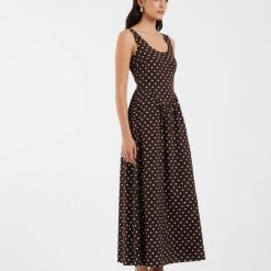 robes longues marron et blanc à pois design sans manches décolleté rond coupe évasée portée par une femme avec des mules noires