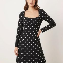 robes longues noires à pois encolure carrée petite delilah portée par un mannequin avec manches longues et coupe élégante