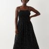 robes à pois blanc et noir froncée longue de plage portée par une femme avec bretelles fines et bustier élastique
