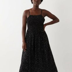 robes à pois blanc et noir froncée longue de plage portée par une femme avec bretelles fines et bustier élastique