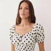 robes à pois blanc et noir longue plage manches bouffantes liens devant une jeune femme portant une robe à pois blancs et noirs avec des manches bouffantes et un lien devant sur fond blanc