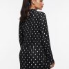 robes à pois blanc et noir manches courte plissée longues portée par une femme vue de dos avec un col montant