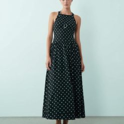 robes à pois blanc et noir bretelles croisées dos effet froissé monochrome robe longue col halter portée par une femme avec des sandales
