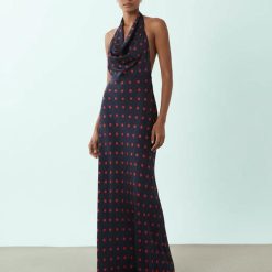 robes à pois marine bénitier col dos nu longue carmin portée par un mannequin sur un fond neutre et clair