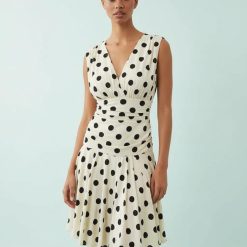 robes en tulle à pois courte moulante avec col v volanté sans manches couleur creme avec des motifs a pois noirs portée par une femme divine