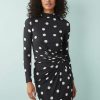 robes à pois hiver manches torsadées col montant stretch longue tissu noirs avec motif à pois blancs sur une femme debout trouve le fond blanc