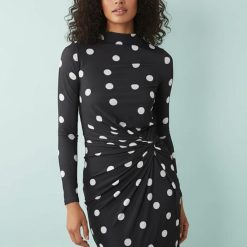 robes à pois hiver manches torsadées col montant stretch longue tissu noirs avec motif à pois blancs sur une femme debout trouve le fond blanc