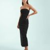 robes longues noires à pois bandeau design moulante sans bretelles ajustée coupe droite portée par un mannequin sur fond bleu clair