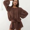 robes manches longues à pois drapée mousseline taille nouée ballon chocolat une femme pose avec un ensemble chic et fluide de couleur marron à pois blancs avec des manches amples et une ceinture nouée à la taille