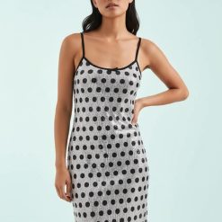 robes à pois transparentes sequins bretelles longueur fantaisie une femme porte une robe blanche transparente à pois noirs et paillettes avec des bretelles noires finesse élégance et chic