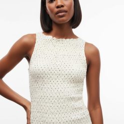 robes asymétriques à pois courte taille basse crème débardeur sans manches ajusté avec un motif à petits pois trouvé sur un mannequin femme noire aux cheveux courts coupe au carré devant un fond blanc