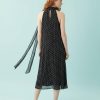 robes à pois jaune dos nu mi longue noir portée par une femme rousse vue de dos sur fond bleu clair