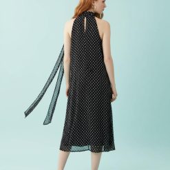 robes à pois jaune dos nu mi longue noir portée par une femme rousse vue de dos sur fond bleu clair