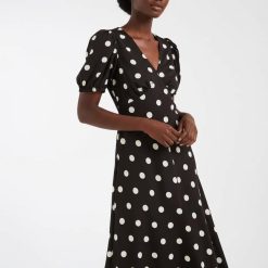 robes à pois jaune v col avec milongue marron chocolat portée par une femme avec des manches courtes
