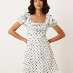 robes à pois transparentes babydoll courte nouée sur devant blanche à motif pois noirs avec manches bouffantes et col volanté