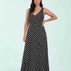 robes évasées à pois bénitier col longue manches sans noir anna dot portée par un mannequin sur fond bleu clair