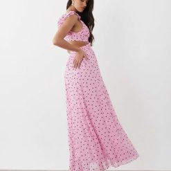 robes mousseline à pois rose vale volantées épaules longue avec découpe à la taille et dos nu portée par un mannequin avec des talons noirs