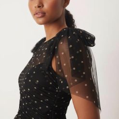 robes longues à pois rouge noirs tulle en nœud avec épaules étagée portée par une femme avec du tissu transparent noir et des pois dorés