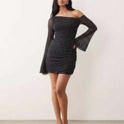robes noires à petit pois dénudées tulle courte épaules ange manches avec des pois blancs fins et des manches longues évasées sur une femme posant sur un fond uni et clair