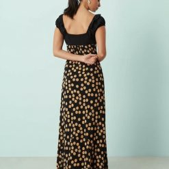 robes rouges à petit pois dégagée noué volants longue détail encolure marron portée par un mannequin blond avec haut noir