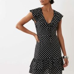 robes à pois noirs et blancs dos longue nu portée par une femme aux cheveux bouclés sur fond blanc